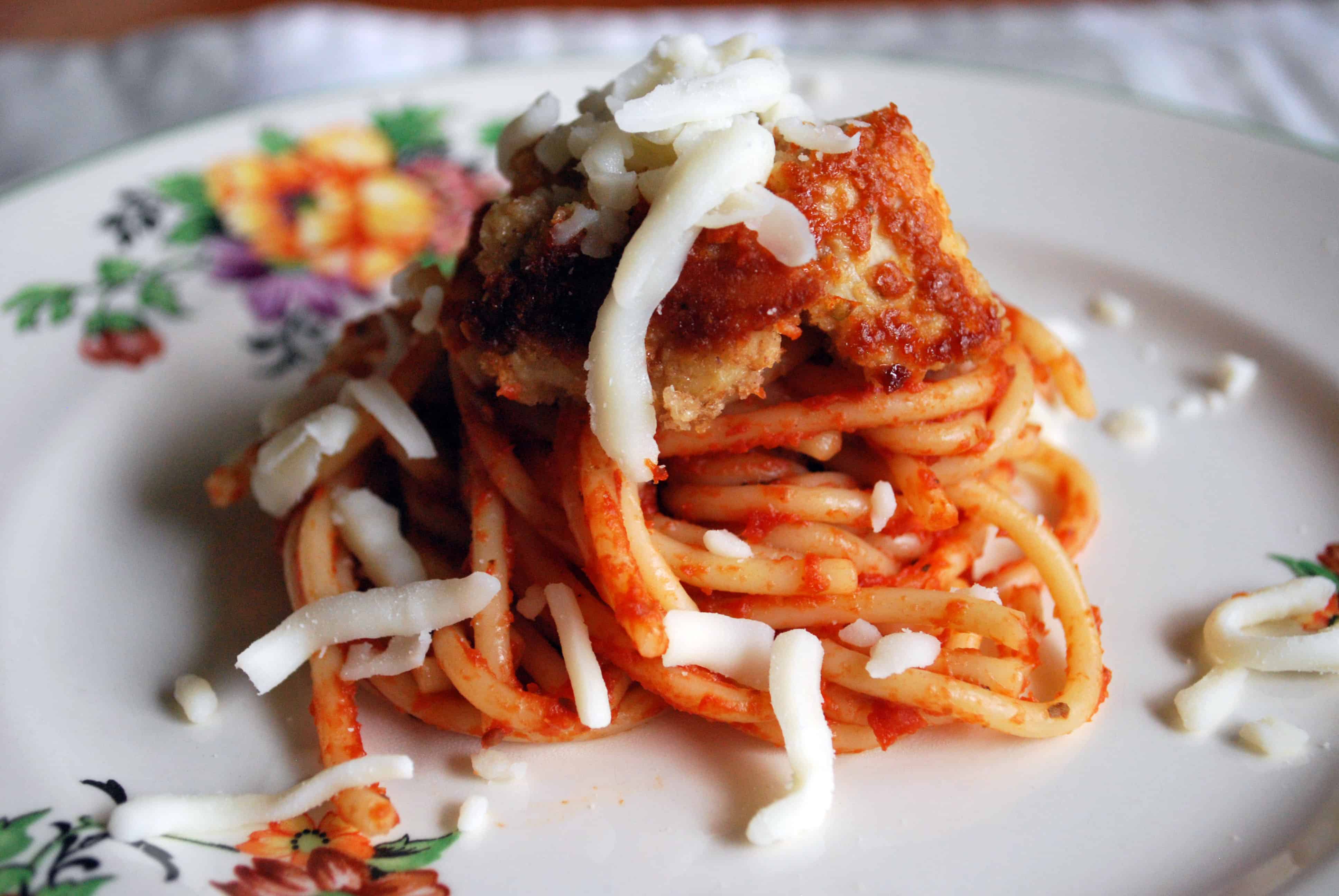 ChickenParmBitesCU Chicken Parm Bites topped with cheese on a white plate with a floral pattern