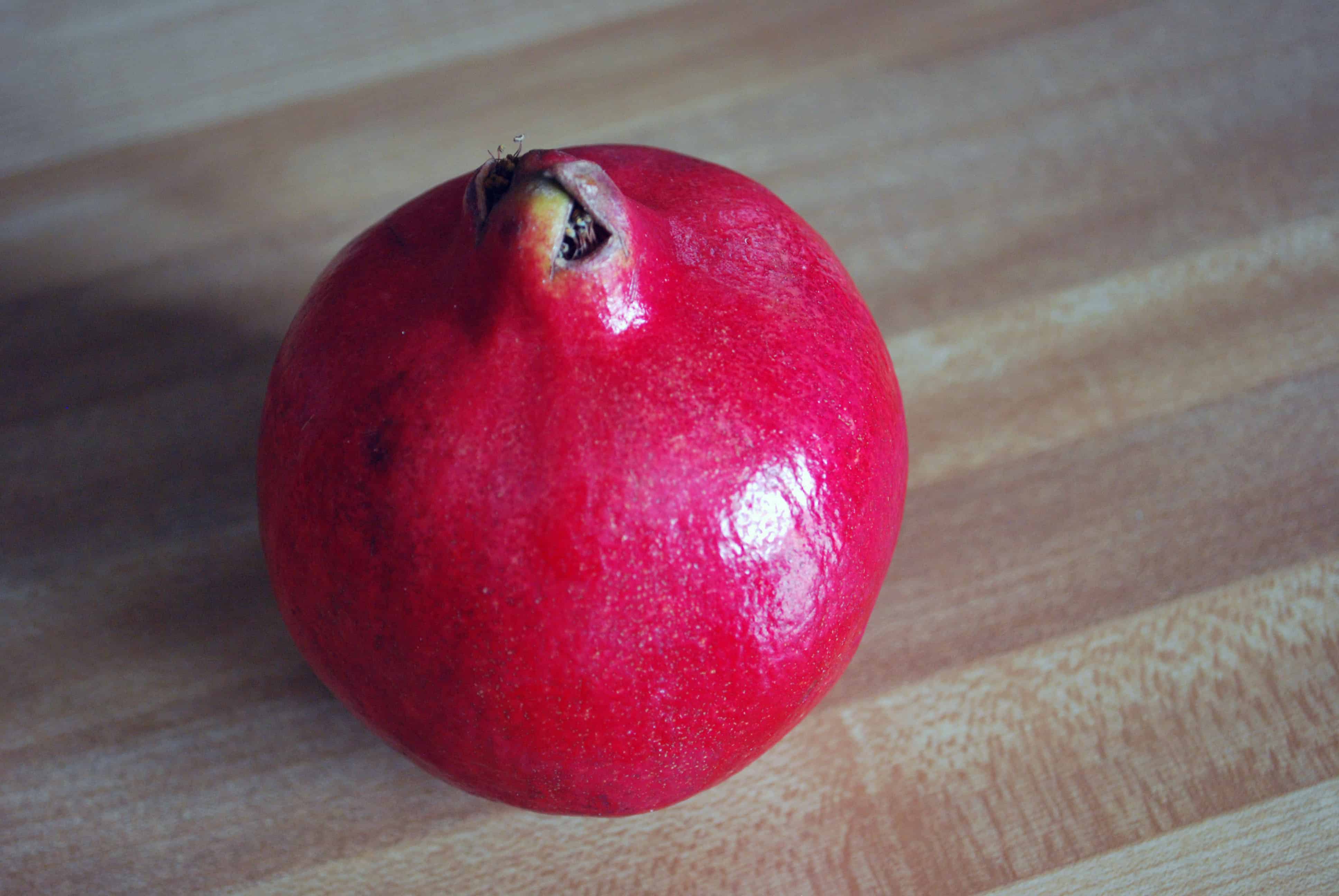 PomegranateWhole whole Pomegranate on a wood cutting board