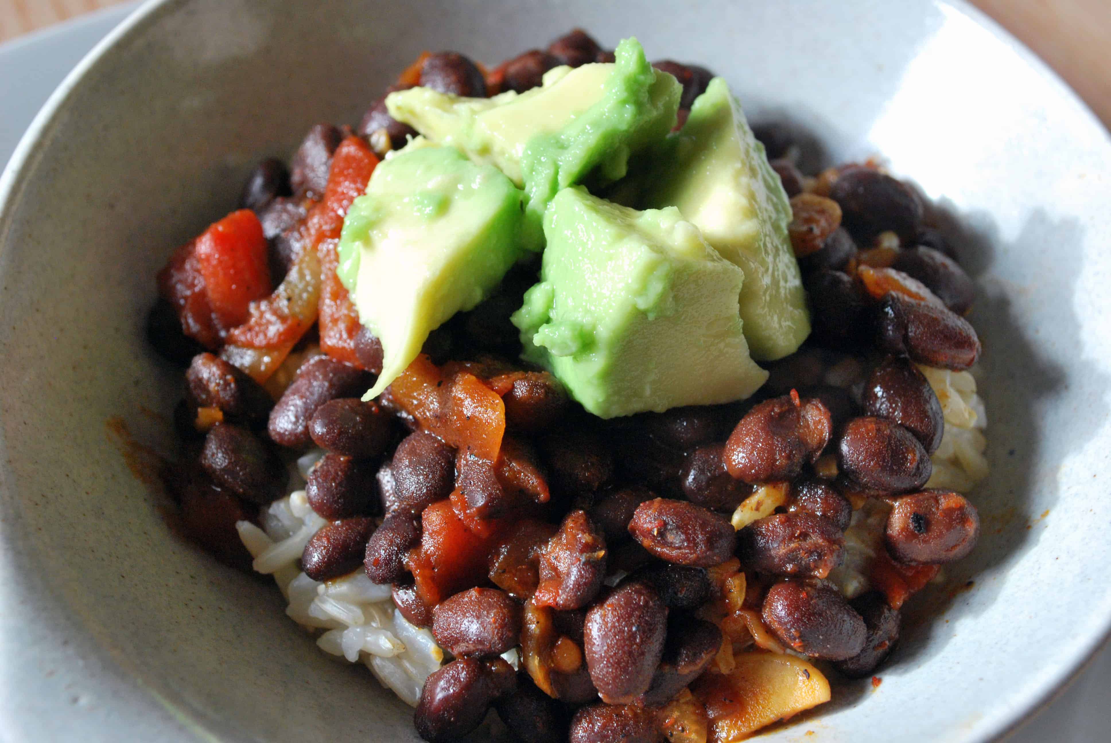 BeerGlazedBlackBeanswithAvocado Beer Glazed Black Beans and avocado on top of rice in a white bowl on a white plate