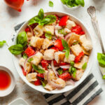 a bowl of panzanella salad with a striped napkin and herbs
