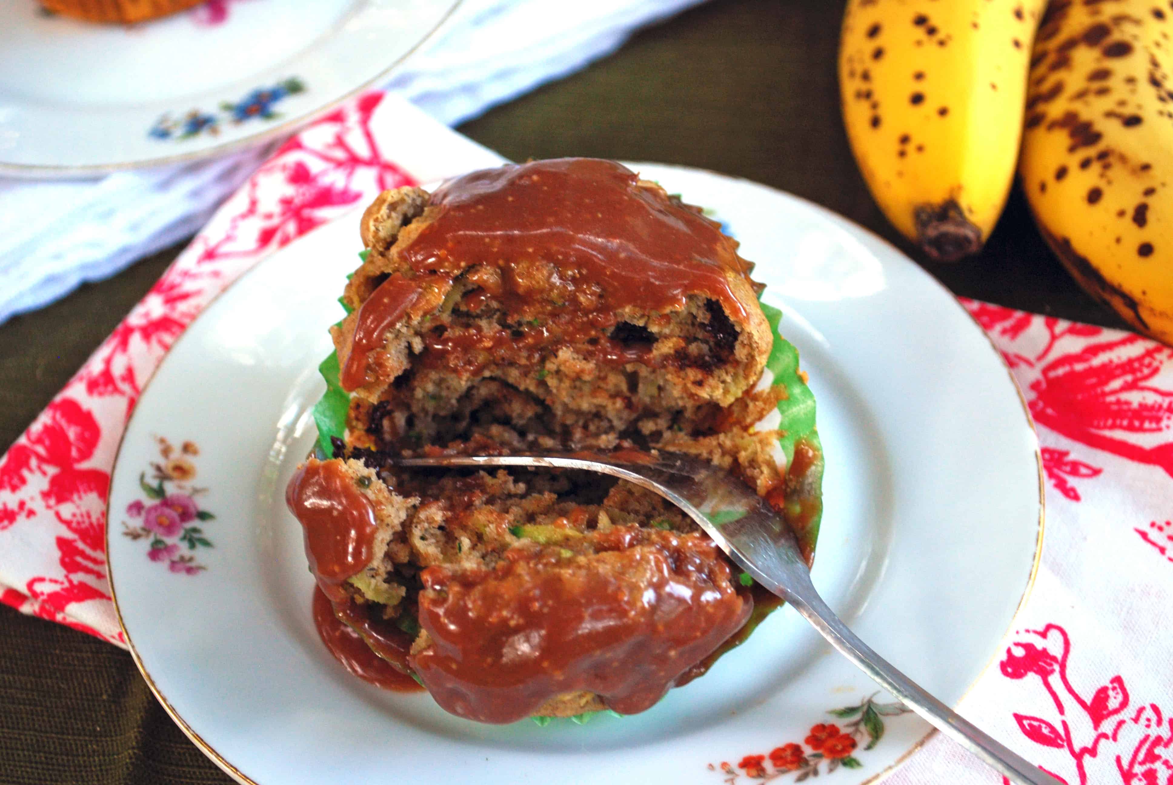 Zucchini Banana Chocolate Chip Muffins with Peanut Butter Nutella Glaze Zucchini Banana Chocolate Chip Muffin on a plate topped with Peanut Butter Nutella Glaze with a fork breaking it in half