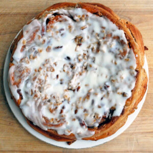 frosted oatmeal pecan cinnamon rolls on a plate on a light wood table