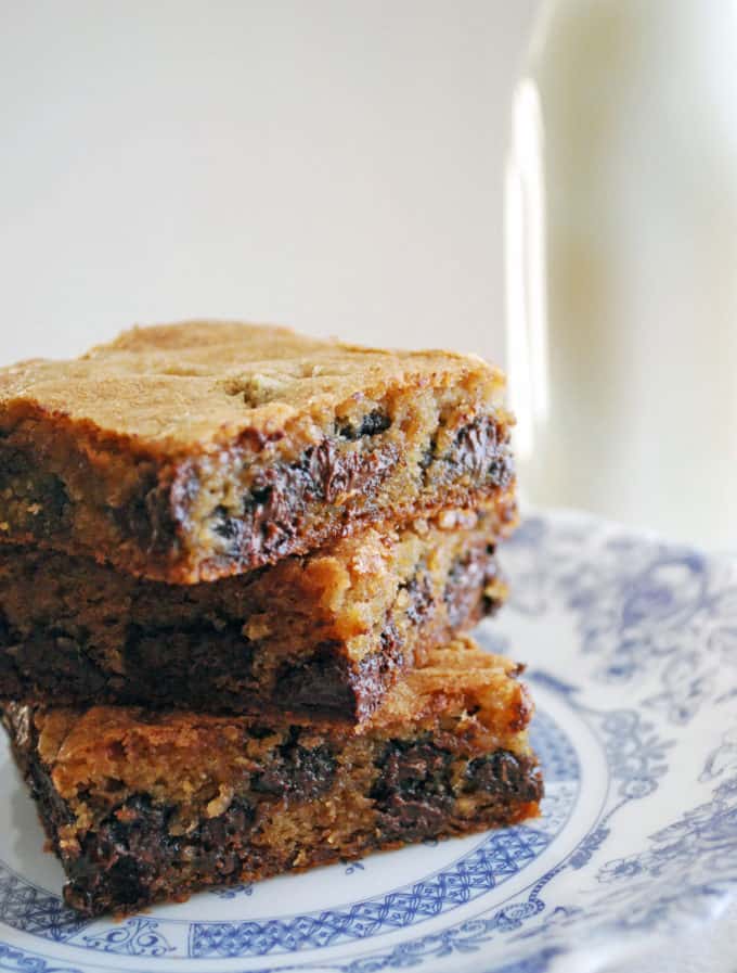 a stack of three chocolate chunk blondies on a blue flowery plate