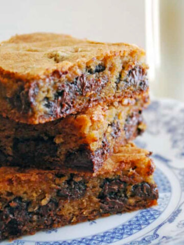 Chocolate Chunk Blondies stacked on a blue and white plate.