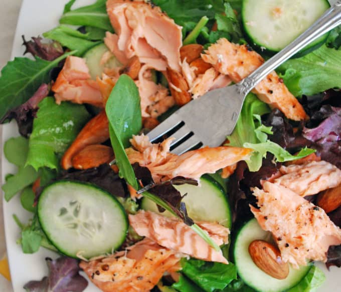 a fork in a salmon and vegetable salad