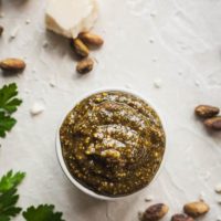 pistachio pesto in a little ramekin with parsley, cheese, and nuts around