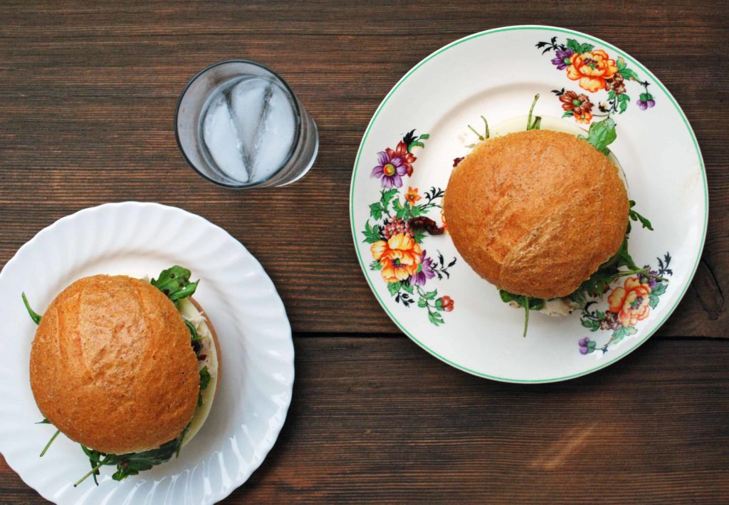 Top down view of two Balsamic and Sun-Dried Tomato Sandwiches and a glass of water.