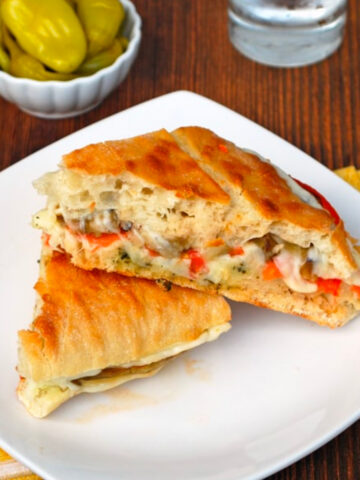 Eggplant Panini cut in half on a white square plate.