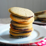 Homemade Milano Cookies stacked on a white plate.