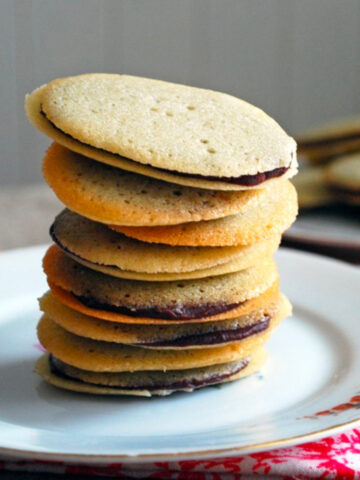 Homemade Milano Cookies stacked on a white plate.