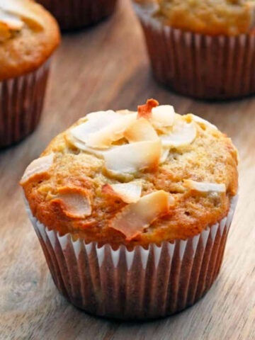 Banana coconut muffins on a wooden surface.