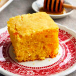 a slice of cornbread on a red and white plate.