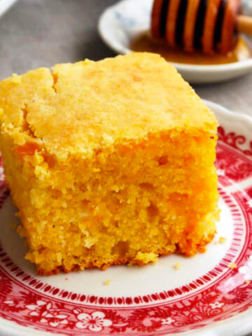a slice of cornbread on a red and white plate.
