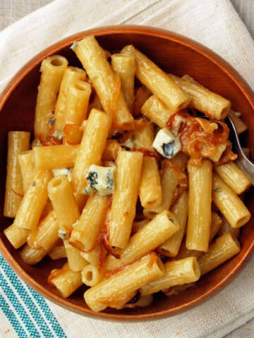 rigatoni with caramelized onions on a wood bowl