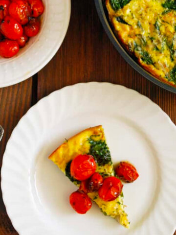 a slice of vegetable frittata topped with tomatoes.