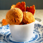 two scoops of salty caramel ice cream in a cup with a few waffle cone pieces