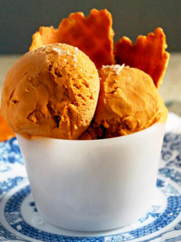 two scoops of salty caramel ice cream in a cup with a few waffle cone pieces