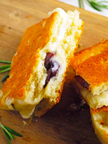 a couple focaccia grilled cheese sandwiches cut in half on a wooden cutting board.