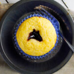 three black raspberry cornbread muffins on plates.