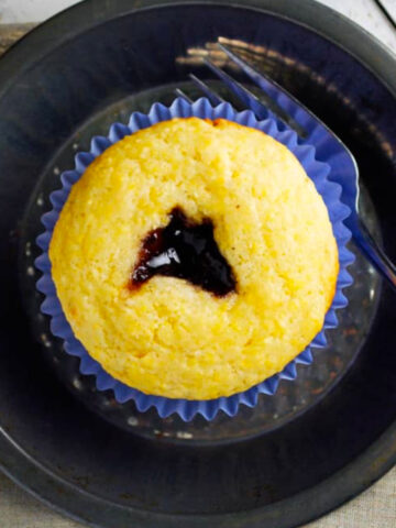 three black raspberry cornbread muffins on plates.