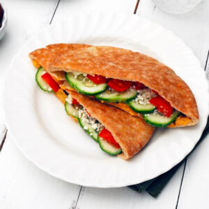 two greek pita sandwiches on a white plate.