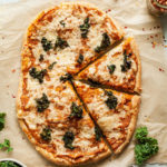 butternut squash pizza with kale on parchment paper
