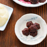 chocolate honey bombs on two plates with another plate of honey.