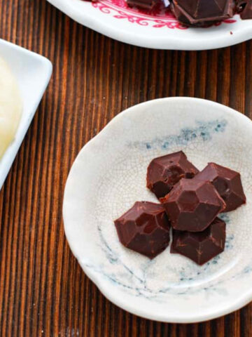 chocolate honey bombs on two plates with another plate of honey.