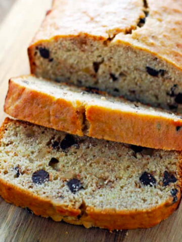 a loaf of banana bread with a few slices cut on a wood cutting board