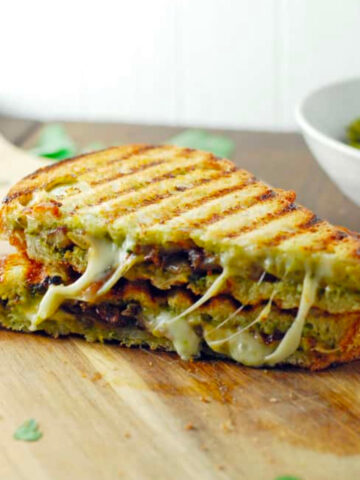 Butternut Squash and Sage Pesto Grilled Cheese cut in half on a cutting board.