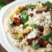 hummus on a white plate loaded with toppings