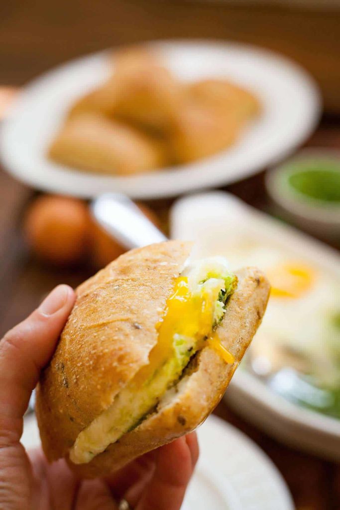 a runny egg sandwich being held by a hand