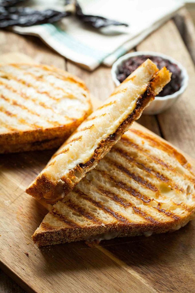 harisssa grilled cheese sandwiches on a wood cutting board