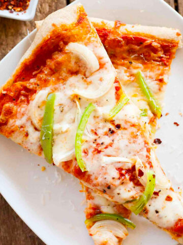 two slices of onion and green pepper pizza on a white plate.
