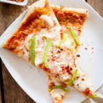 two slices of onion and green pepper pizza on a white plate