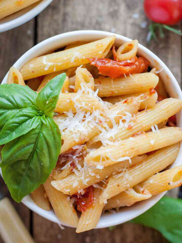 roasted tomato penne in a white bowl with basil