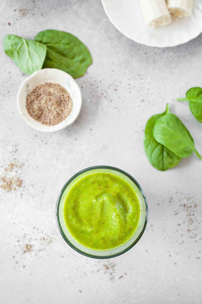 top view image of green smoothie with ingredients on table