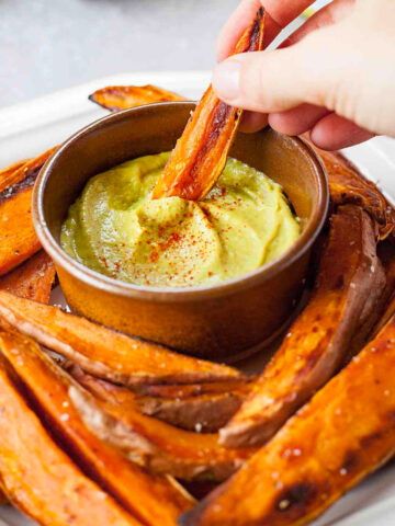Sweet potato wedges with one being dipped into honey mustard dressing.