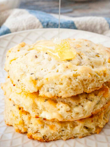 image of side of biscuits on white plate with honey being drizzled on top