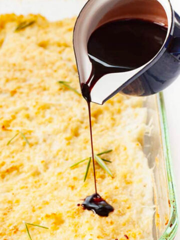 Mashed Potato Bake with Red Wine Balsamic Reduction being poured onto mashed potato bake