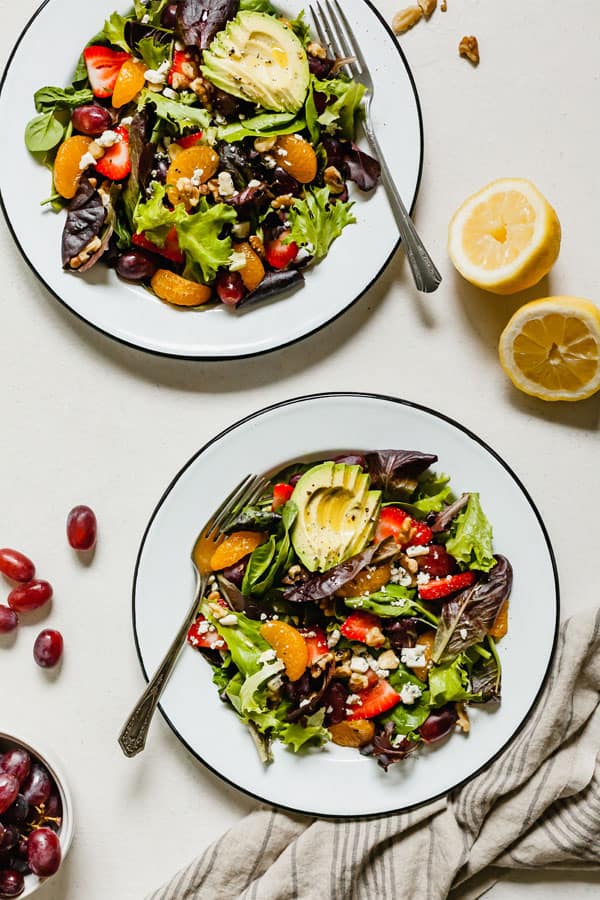 image of two plates with summer salad with fruit on the table
