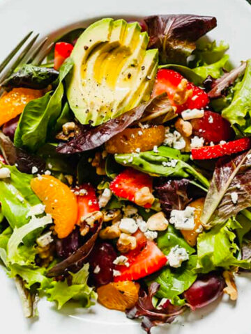 image of a plate with summer salad with fruit on the table.