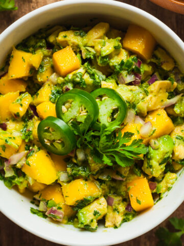 Mango Salsa with Avocado in a bowl topped with jalapeño slices.