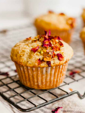side shot of pistachio rose muffins on baking sheet with muffins in background.