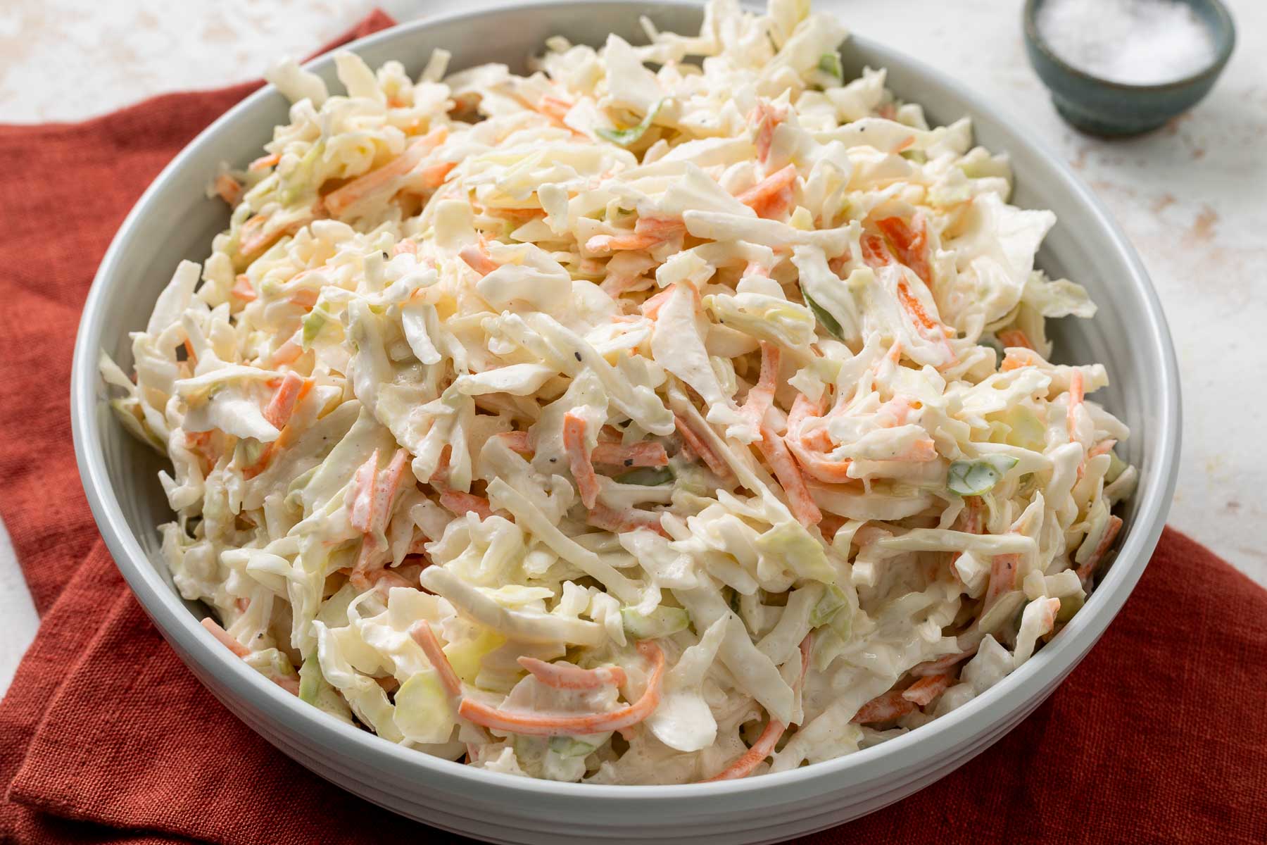 A bowl of no-mayo coleslaw on a red linen napkin.