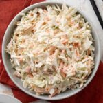 A bowl of no-mayo coleslaw on a red linen napkin.
