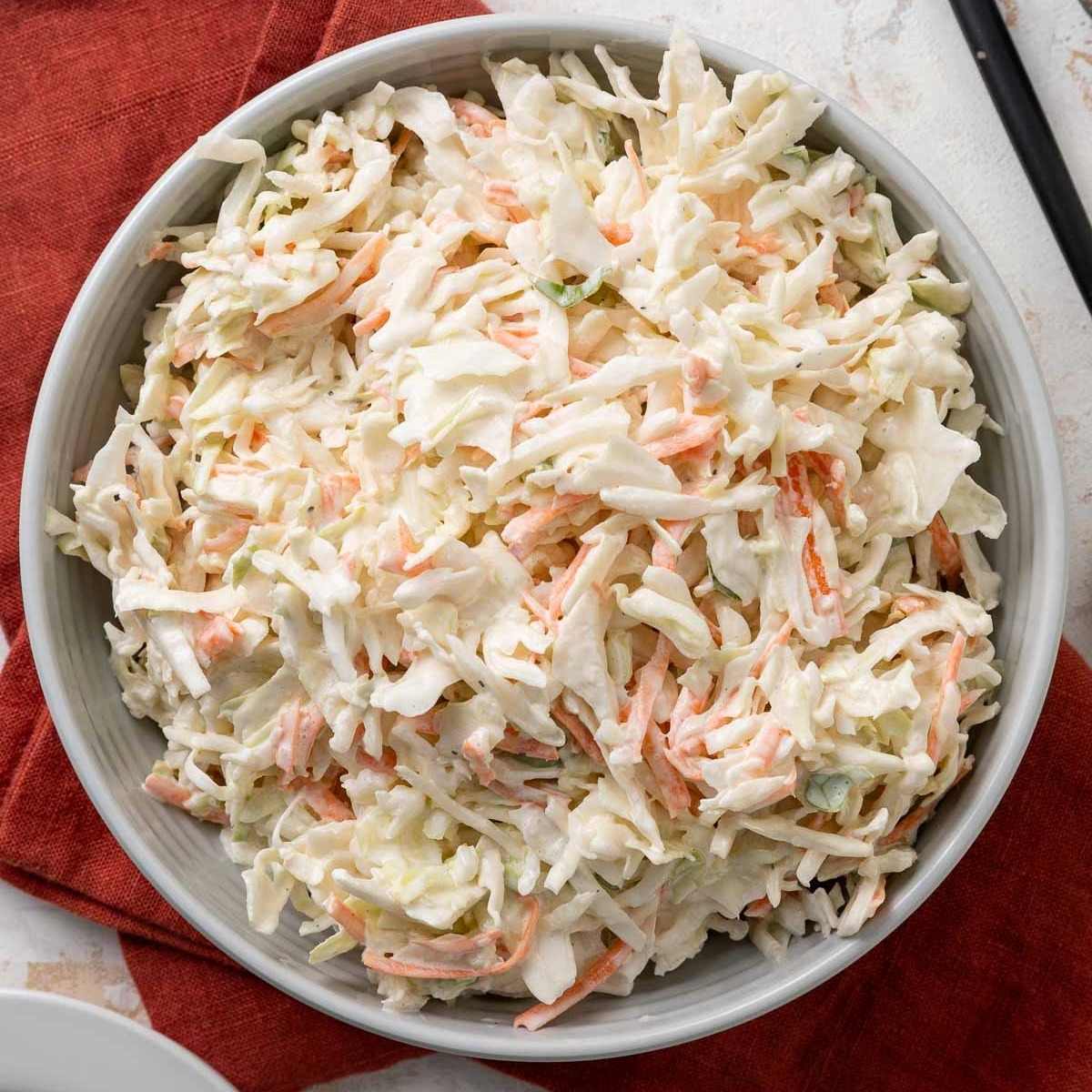A bowl of no-mayo coleslaw on a red linen napkin.