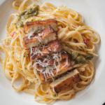 cajun tofu sliced over fettuccine alfredo on a white plate