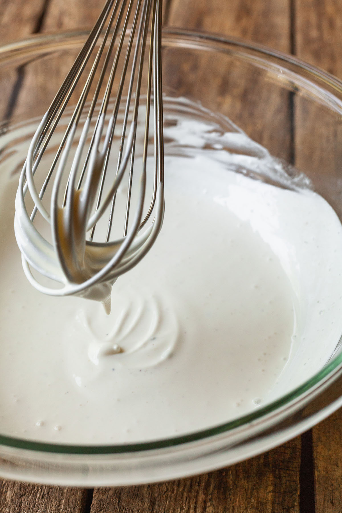 a whisk stirring the dressing for no mayo coleslaw.