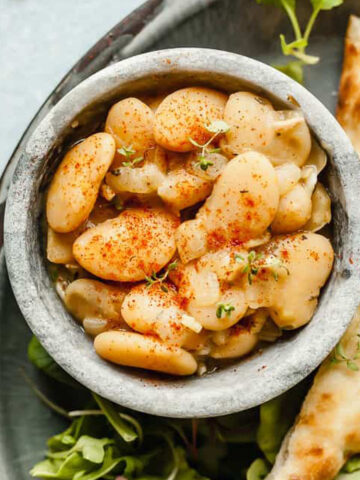 butter beans in a bowl on a plate with toast and microgreens